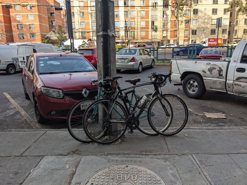 Dos bicicletas recargadas en un poste de luz, esperando su oportunidad de ser parte de un recorrido urbano
